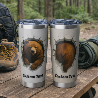 Two silver tumblers with bear design on a wooden surface outdoors.