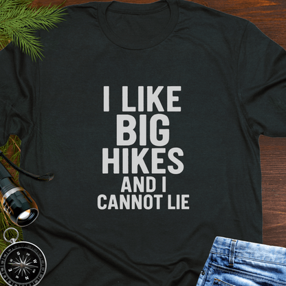Black t-shirt with 'I LIKE BIG HIKES AND I CANNOT LIE' text on a wooden surface with hiking accessories.