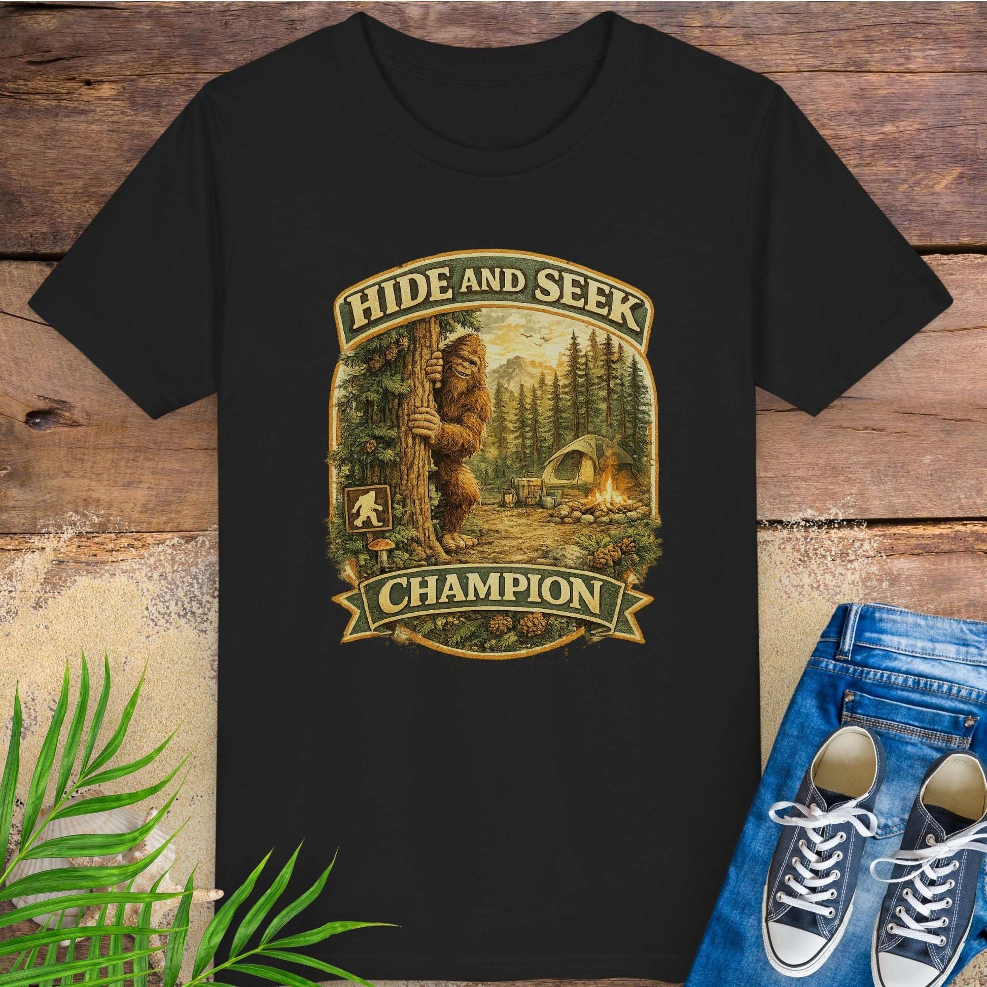 Black t-shirt with 'Hide and Seek Champion' graphic featuring a bigfoot in a forest on a wooden surface.