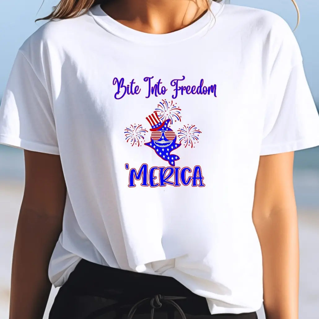 A Woman wearing a white t-shirt with a patriotic shark with red and white striped glasses, a patriotic top hat with fireworks around that says Bite Into Freedom "merica.