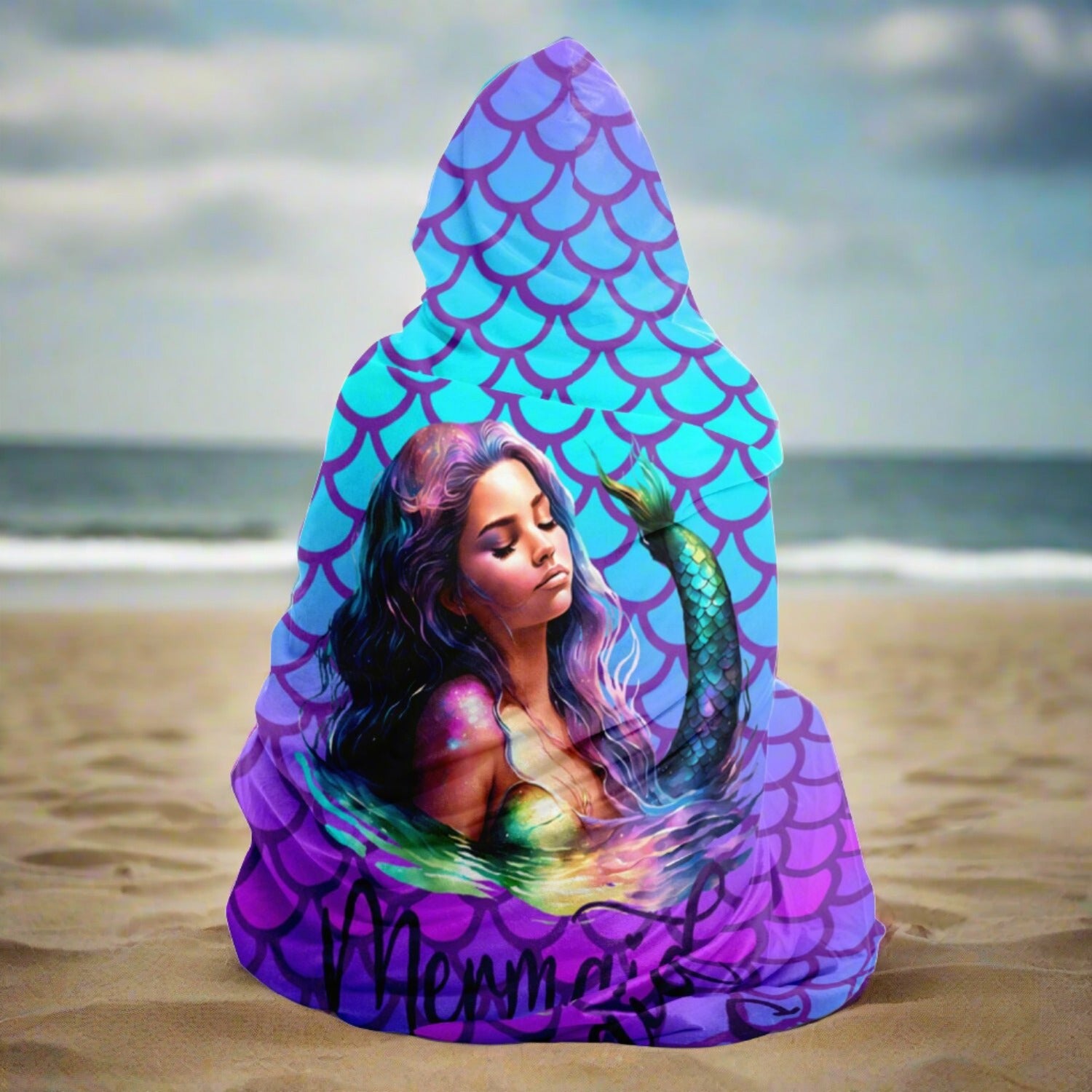 Person wearing a hooded blanket with mermaid scales in purple and turquoise with a picture of a beautiful mermaid with the words mermaid vibes below