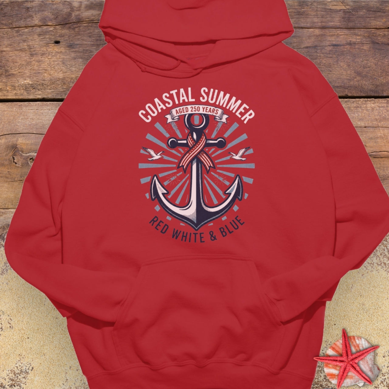 Red hoodie with an anchor design and text on a wooden surface