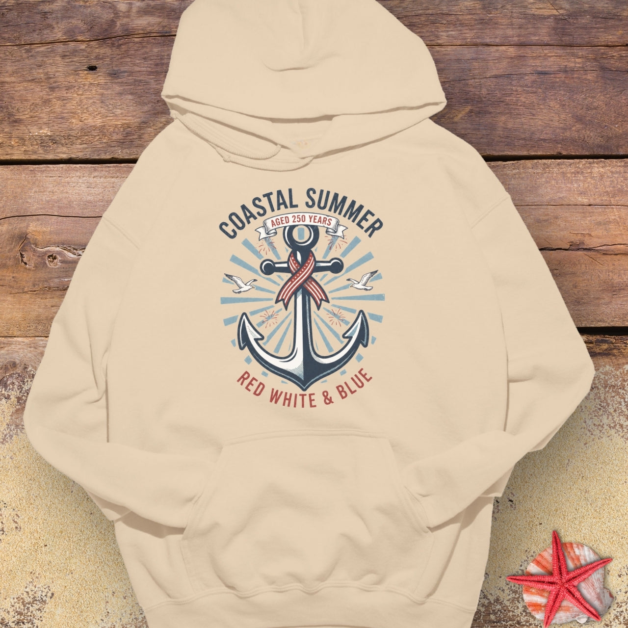 Beige hoodie with an anchor design on a wooden surface with a starfish.