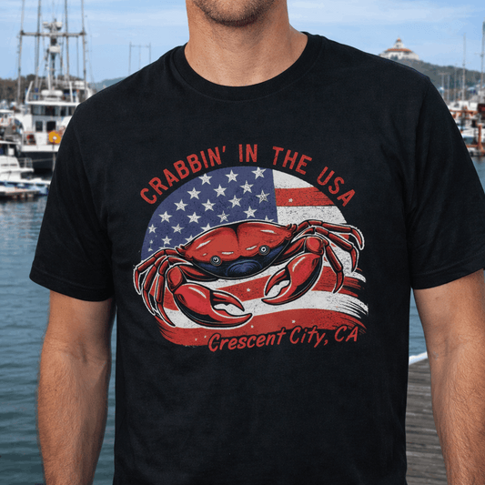 Person wearing a black t-shirt with a crab graphic over the US flag with the text Crabbin' in the USA Crescent City, CA.