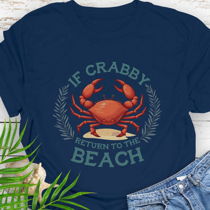 Navy blue t-shirt with a red crab graphic and text 'If Crabby Return to the Beach' on a wooden surface with leaves and jeans.