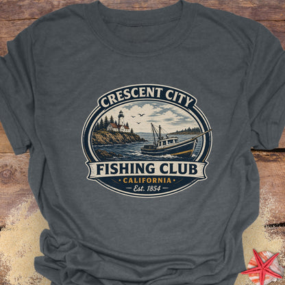 A dark gray crewneck t-shirt featuring a vintage-style circular graphic that reads 'Crescent City Fishing Club California Est. 1854' with an illustration of a lighthouse, boat, and ocean.