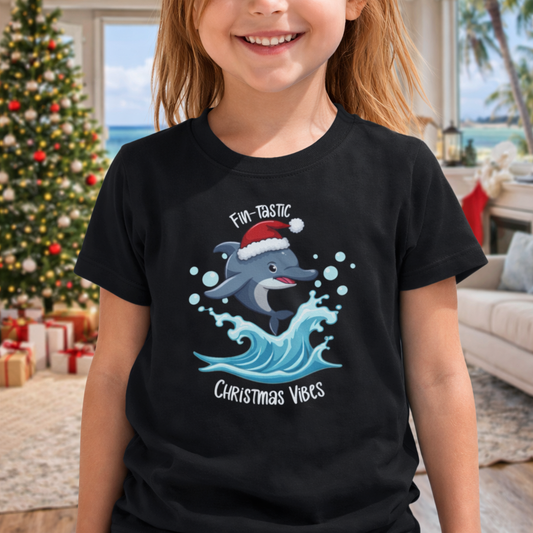 Child wearing a black youth t-shirt with dolphin wearing a Santa hat jumping over a wave and text “Fin-tastic Christmas Vibes”
