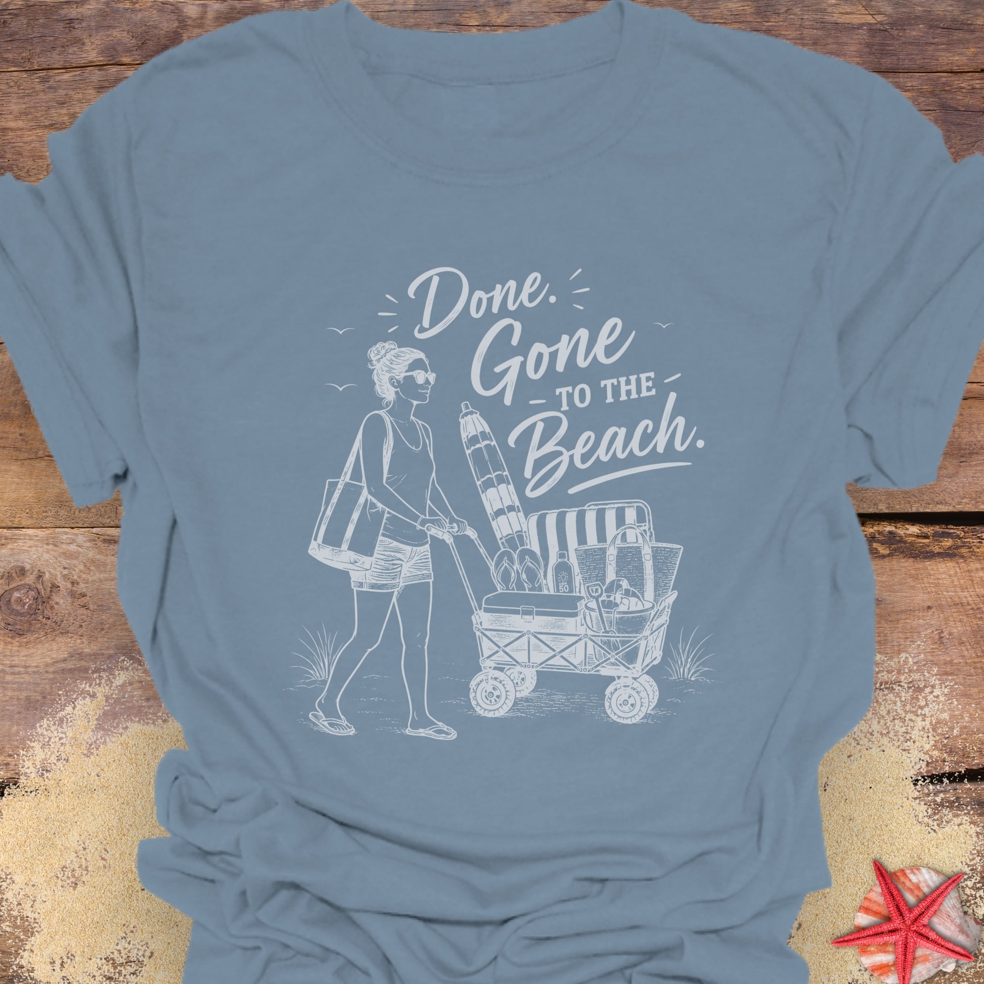 Stone Blue unisex t-shirt with a woman pushing a cart of beach equipment and text "Done. Gone to the Beach."