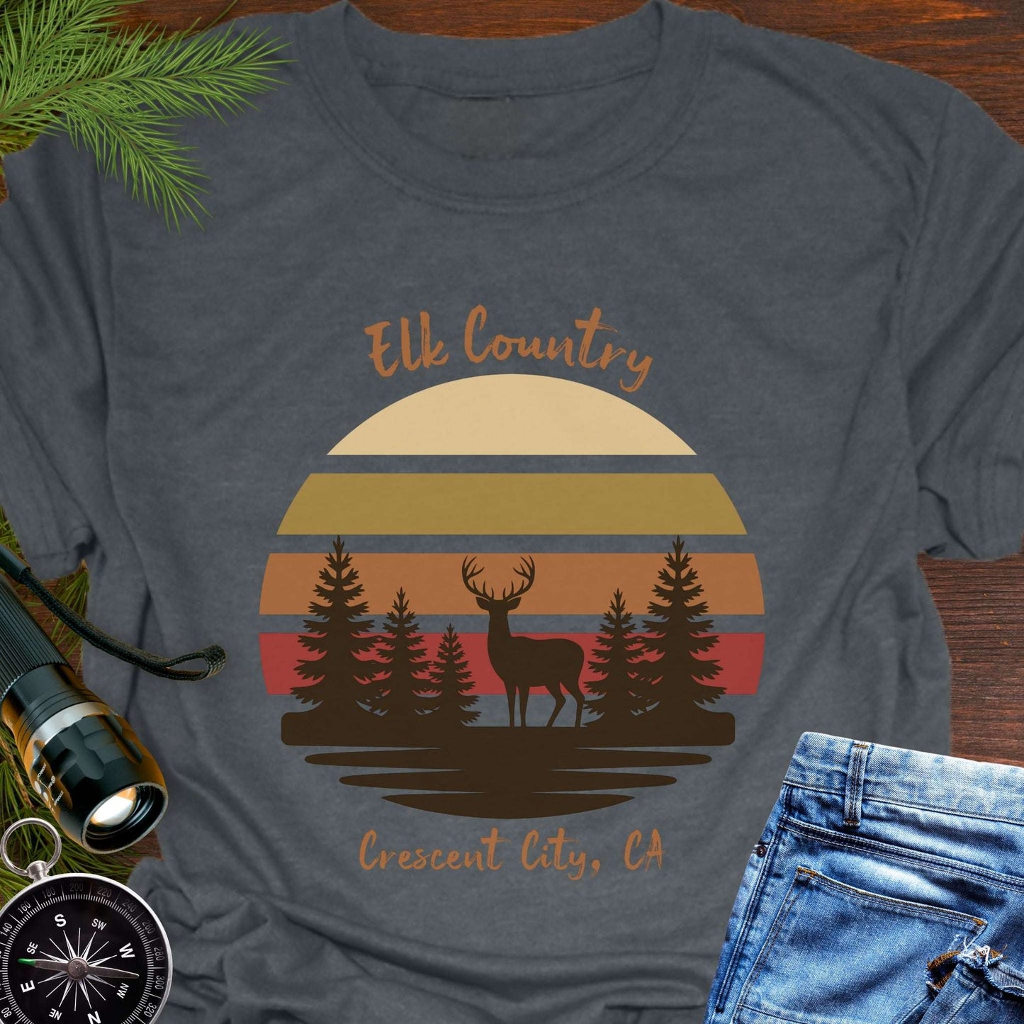 Gray t-shirt with muted retro sunset with brown silhouette deer and trees with text 'Elk country Crescent City, CA.