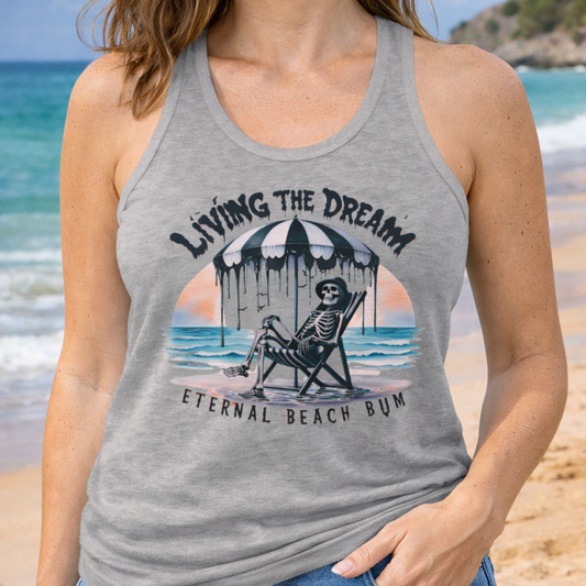 Person wearing a tank top with a beach-themed skeleton on beach with text Living the Dream Eternal Beach Bum.