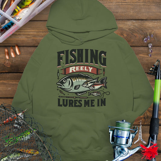 Military Green fishing hoodie with fish and tackle graphics and the phrase “Fishing Reely Lures Me In”.