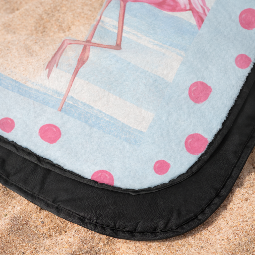 Outdoor beach blanket with flamingo design close-up.