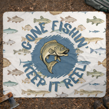 Outdoor blanket with fish illustrations and text 'Gone Fishin' Keep It Real' on a textured surface.