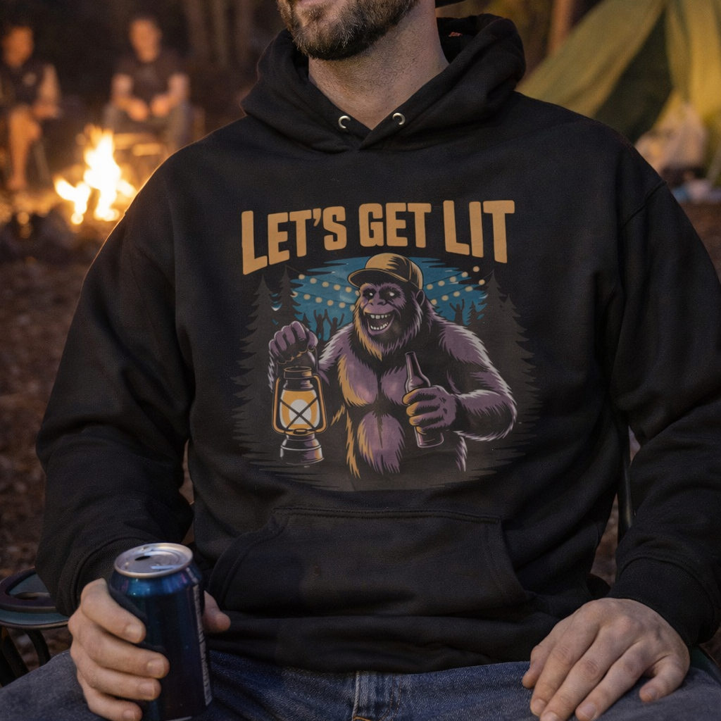 Man wearing a hoodie with 'Let's Get Lit' graphic with a bigfoot holding a lantern in the forest for camping.