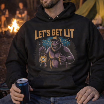 Man wearing a hoodie with 'Let's Get Lit' graphic with a bigfoot holding a lantern in the forest for camping.