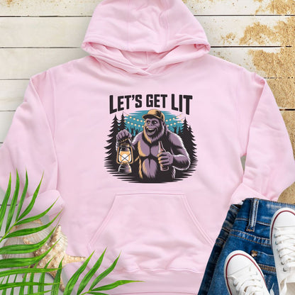 Pink funny Sasquatch camping unisex hoodie with relaxed outdoor party vibe that says Let's Get Lit featuring a sasquatch wearing a ball cap holding a camping lantern and a bottle of beer with the forest in a forest camp scene.