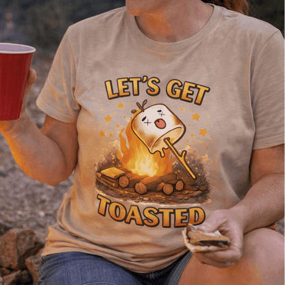 Person wearing a 'Let's Get Toasted' t-shirt by a campfire