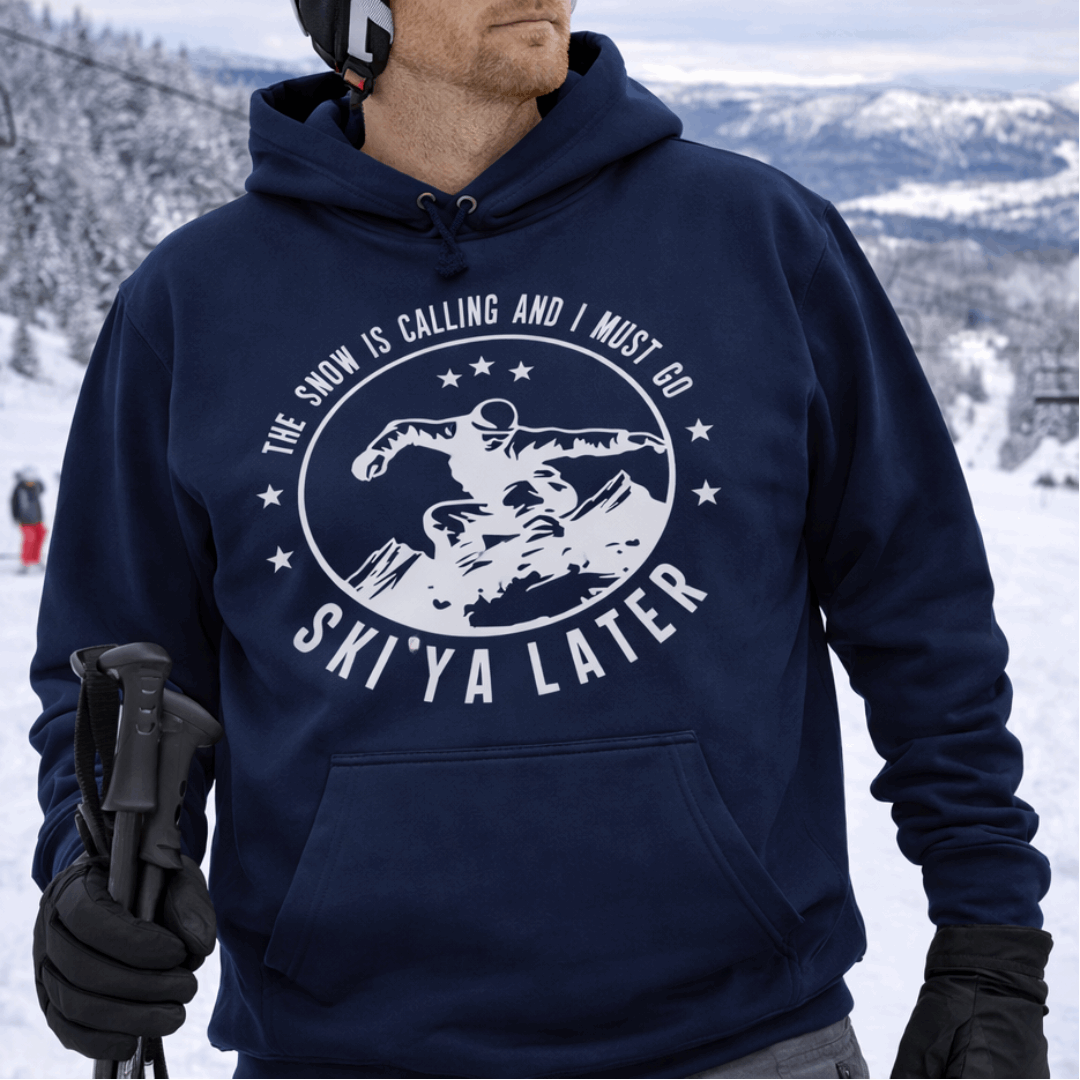 Person wearing a navy hoodie with a skiing design and text Snow is Calling and I Must Go Ski Ya Later.