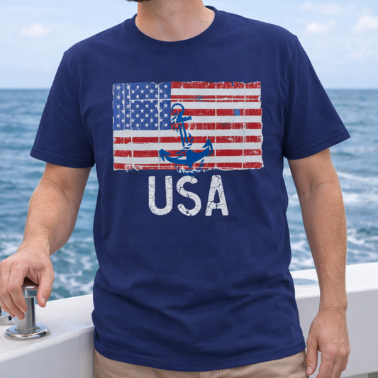 Person wearing a navy blue t-shirt with an American flag and anchor design, standing on a boat with water in the background.