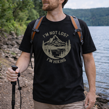 Man hiking by a lake wearing a black t-shirt with 'I'm not lost, I'm hiking' design.