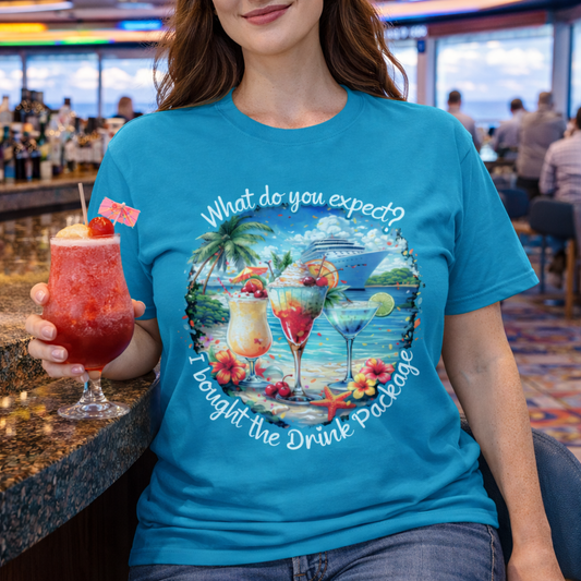 Tropical blue unisex t-shirt with tropical cocktail and cruise ship graphic and text "What do you expect? I bought the drink package"