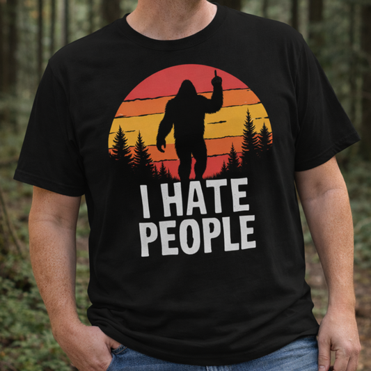 Person wearing a black t-shirt with a 'I Hate People' graphic in a retro sunset forest setting with a silhouette of sasquatch with attitude.