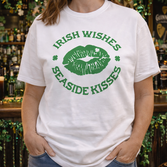 Person wearing a white t-shirt with green text Irish Wishes Seaside Kisses with green kiss lips in the middle.