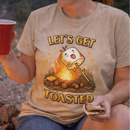 Person wearing a 'Let's Get Toasted' t-shirt by a campfire