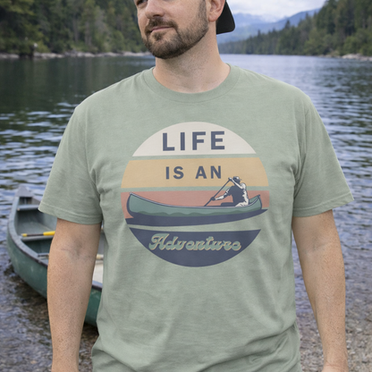 Man wearing a t-shirt with 'Life is an Adventure' graphic by a lake.