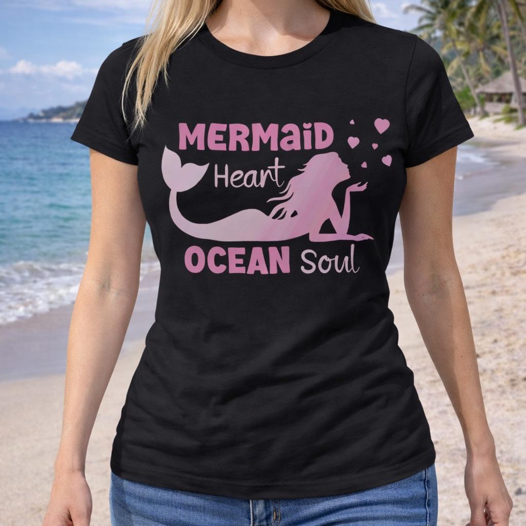 Person wearing a black woman's t-shirt with a mermaid laying on her stomach blowing hearts with text Mermaid Heart Ocean Soul. 
