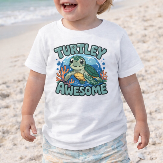 Child wearing a 'Turtley Awesome' sea turtle shirt on a beach.