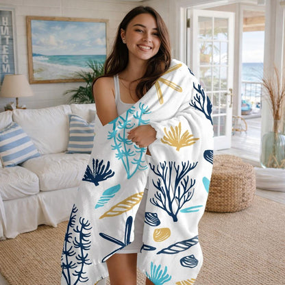 Woman holding a white blanket with blue and yellow coral patterns in a living room.