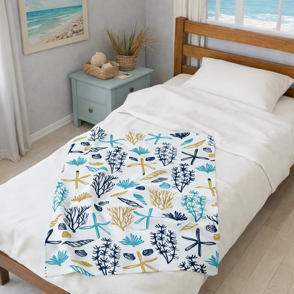 Bed with a colorful coral and starfish patterned blanket in a room with a beach-themed decor.