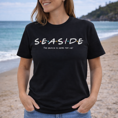 Person wearing a black t-shirt with 'SEASIDE' text on a beach