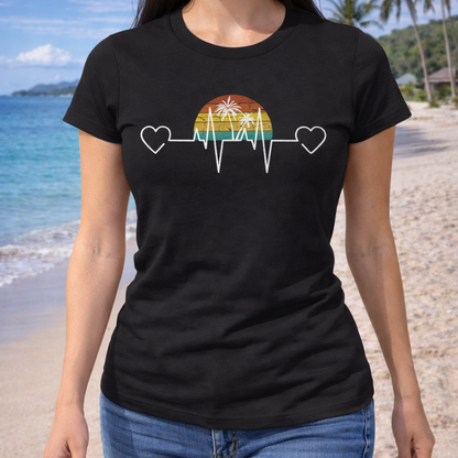 Person wearing a black t-shirt with a heartline with hearts and palm trees over a retro sunset design on a beach