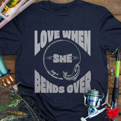 Navy T-shirt with a fishing pole bending over and the phrase “Love When She Bends Over” – humorous fishing design for anglers.