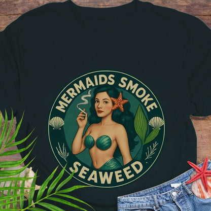 Black t-shirt with mermaid graphic and 'Mermaids Smoke Seaweed' text on a wooden surface.