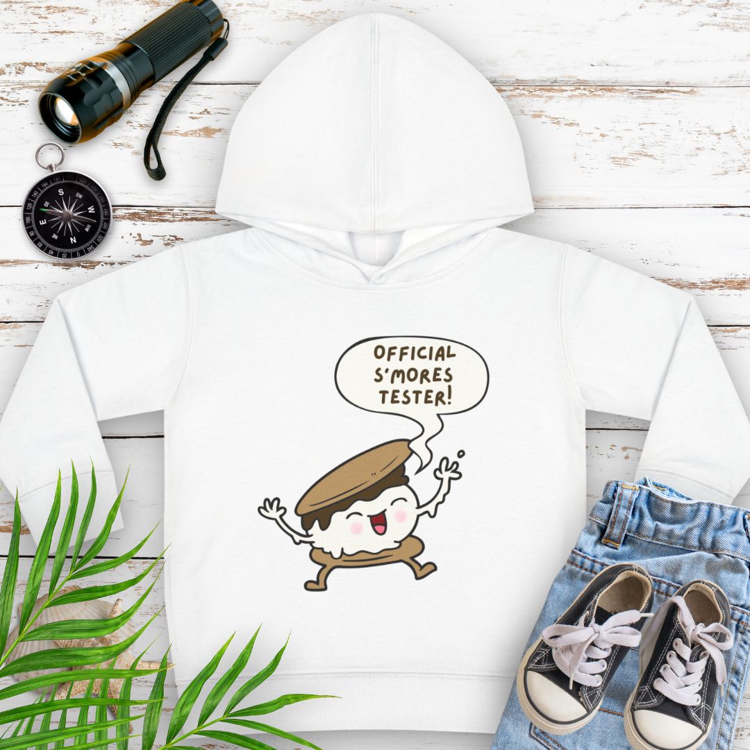 White cozy toddler hoodie with “Official S’mores Tester” speech bubble and a cartoon s'more  – cute outdoor-themed sweatshirt for little campers.