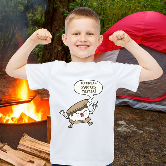 Child wearing white child’s t-shirt with "Official S’mores Tester"  speech bubble and cartoon s'more– fun campfire-themed shirt for kids.