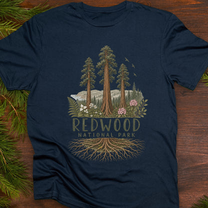 Unisex navy blue T-shirt featuring a detailed Redwood National Park design with towering redwood trees, forest landscape, wildflowers, and exposed roots.