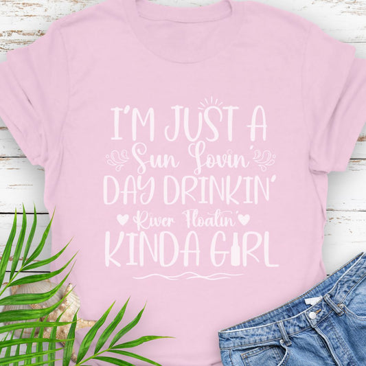 Pink Unisex t-shirt with the phrase "Sun-loving, Day-drinking, River-floating Kind of Girl" printed on the front with embellishments, featuring a relaxed fit and soft cotton fabric.