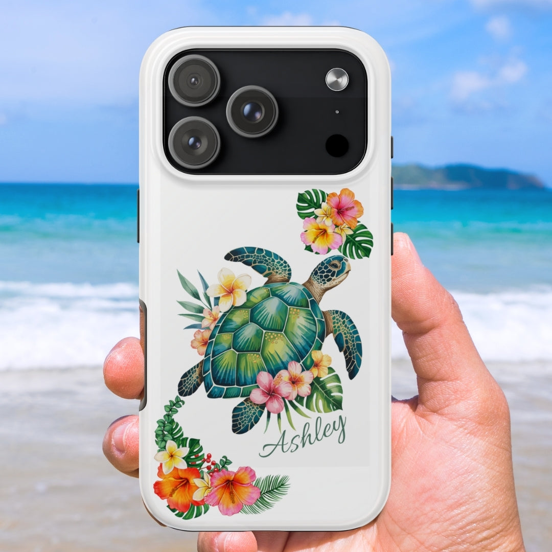 iPhone case with a sea turtle design with hibiscus flowers and can be personalized held against a beach background.