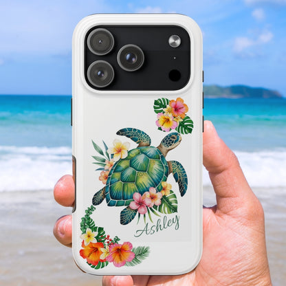 iPhone case with a sea turtle design with hibiscus flowers and can be personalized held against a beach background.