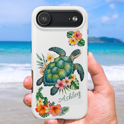 Phone case with a sea turtle design with hibiscus flowers and can be personalized held against a beach background.