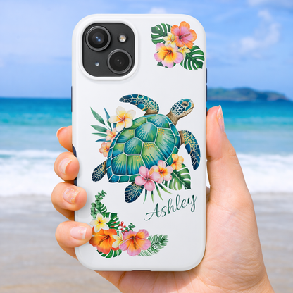 iPhone 17 phone case with a sea turtle design with hibiscus flowers and can be personalized held against a beach background.