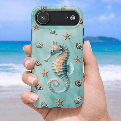 iPhone 17 air phone case with seahorse and shell design held by a hand on a beach background