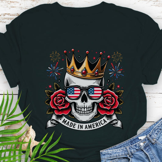 Black T-shirt with  a skull wearing a crown and American flag sunglasses, surrounded by red roses with fireworks in the background and a "Made in America" banner.