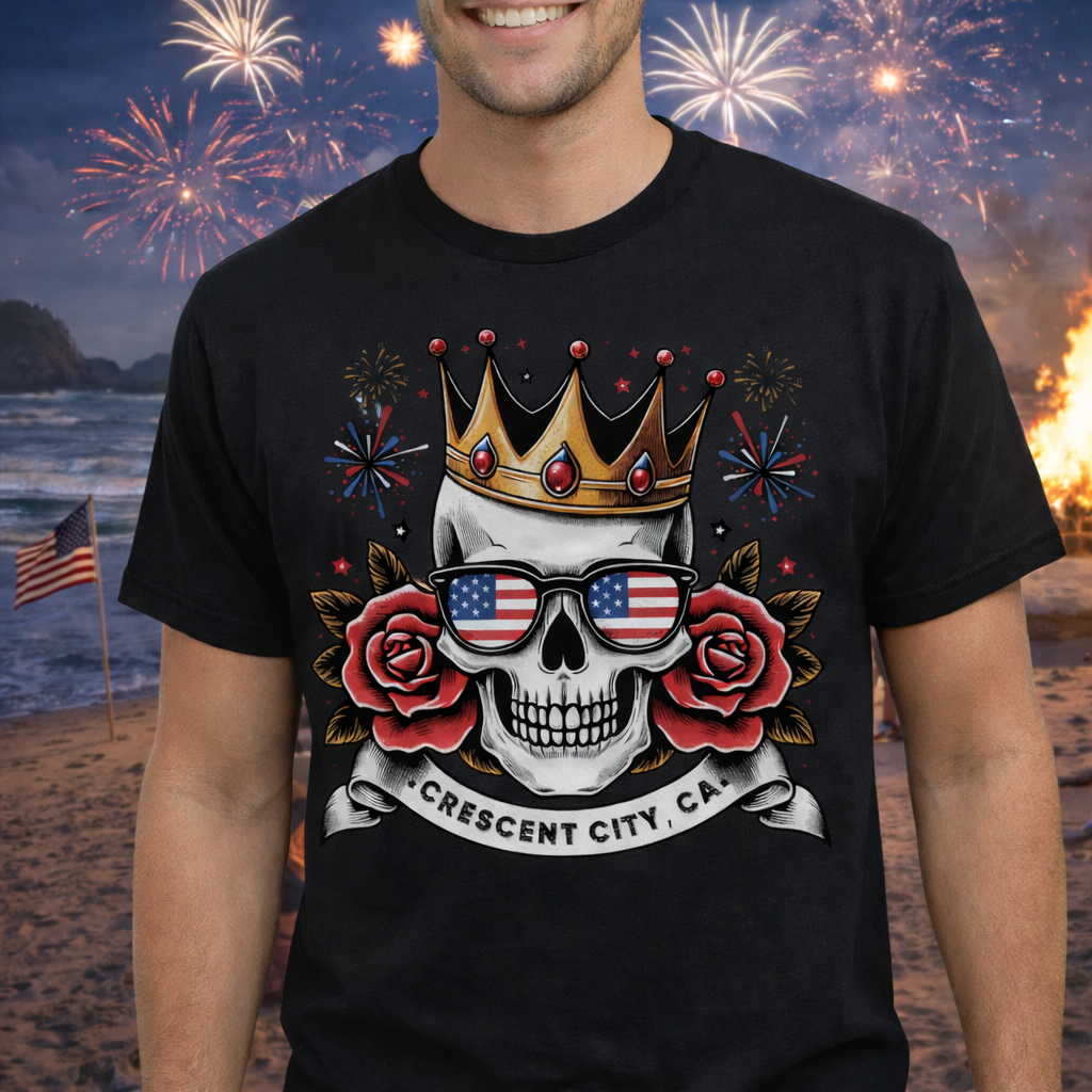 Person wearing a black t-shirt with a skull wearing American flag sunglasses, roses, and a crown with a Crescent City, CA banner below.