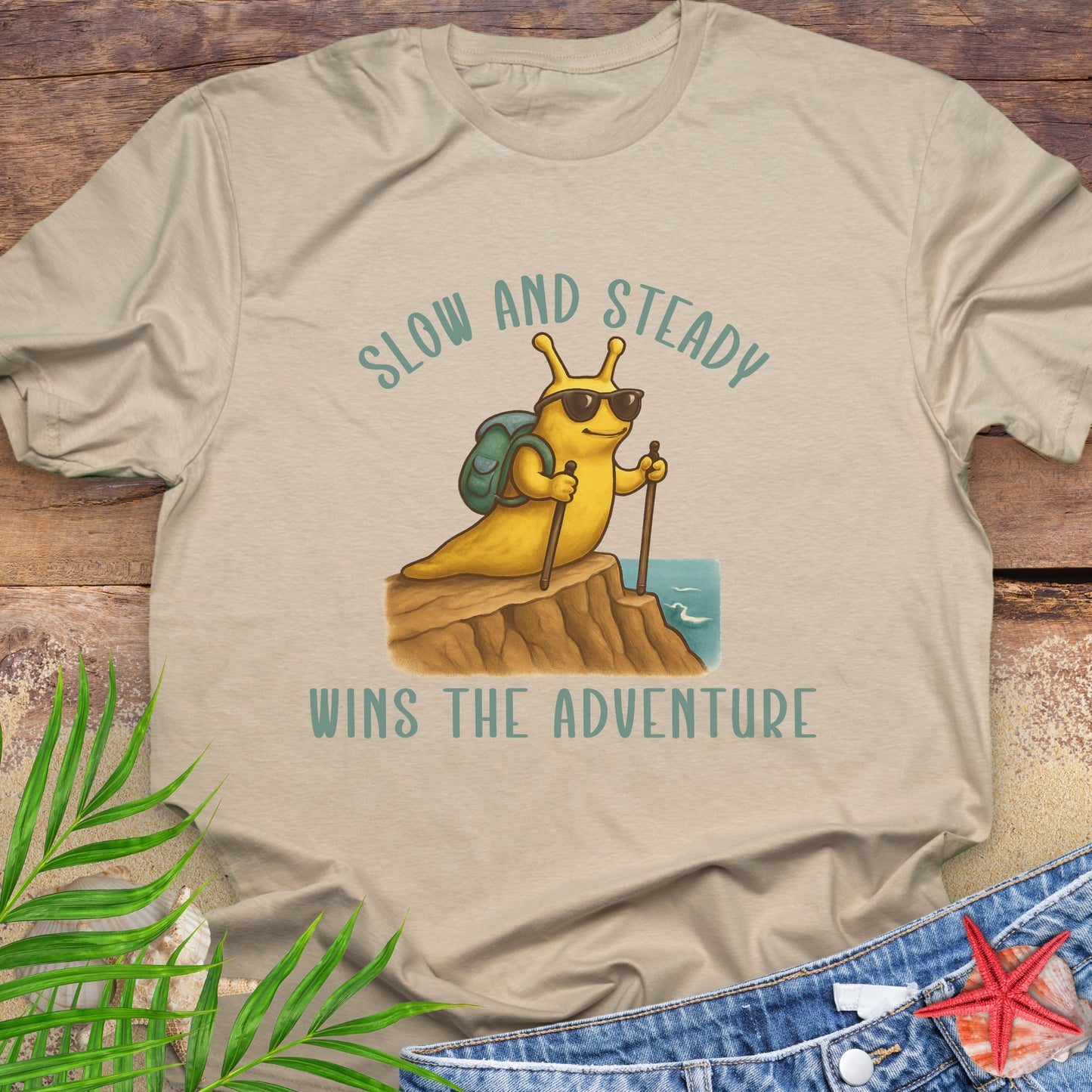 Beige t-shirt with a cartoon character and 'Slow and Steady Wins the Adventure' text.