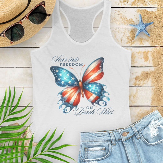 White patriotic women’s tank top with a American flag butterfly design and “Soaring into Freedom” slogan, featuring a scooped neckline and tear-away label.